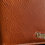**Close-up of a new DuPont leather wallet.** Focus on the texture of the leather, the stitching, and the overall elegant design. Emphasize the feeling of luxury and quality. Use natural lighting.